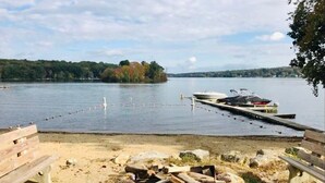 A lakeside dock with a boat, wooden benches, and a clear view of the lake and distant trees. - Lakefront - King - W&D - PetsOK - Kayaks - SUPs (Coventry)