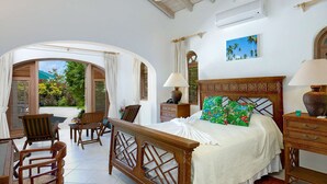 Una habitació espaiosa amb un llit gran, mobles de fusta i vista cap a l'exterior.