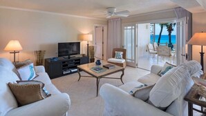 A spacious living room with a flat-screen TV, two sofas, a coffee table, and a balcony with a view of the ocean. - Reeds House Penthouse 14 (2/3 Rooms) (Lower Carlton)