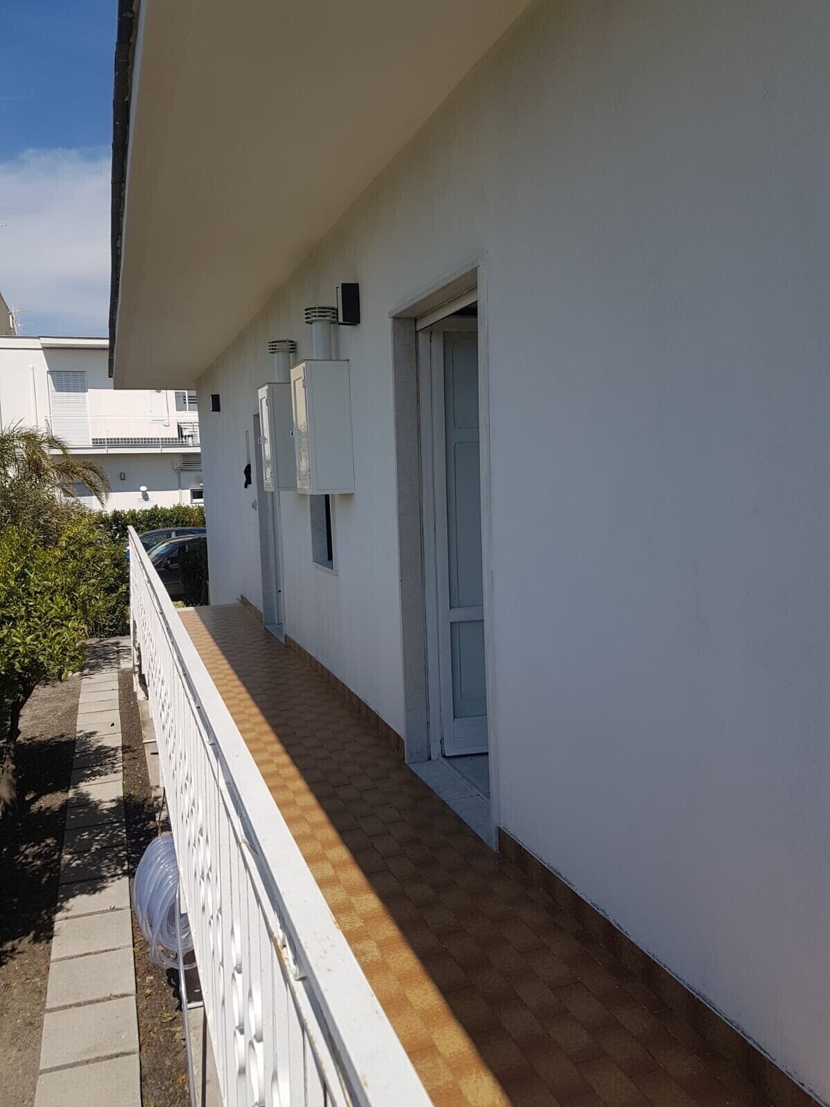 Un edificio blanco con un balcón cubierto, una puerta y una ventana.