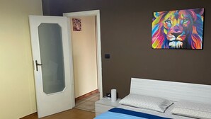 A bedroom with a bed, a nightstand, a wall-mounted air conditioner, a door, and a painting. - B&B Villa Colomba (Torre del Greco)