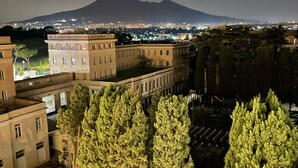 A nighttime view of a cityscape with buildings, trees, and a mountain in the background. - B&B Villa Colomba (Torre del Greco)