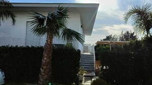 A modern house with a white exterior, a palm tree, and a staircase leading to the entrance. - B&B Villa Colomba (Torre del Greco)