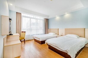 Une chambre d’hôtel avec deux lits, un bureau, une chaise et une grande fenêtre avec des rideaux.