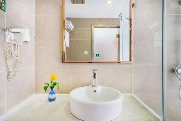 A bathroom with a round white sink, a mirror, a hairdryer, and a vase with a yellow flower. - Homeinn Pebble Hotel (Hangzhou California Sunshine Jinji Road Subway Station) (Hangzhou)