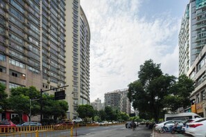 A street view with tall residential buildings, parked cars, and a clear sky. - Homeinn Pebble Hotel (Hangzhou California Sunshine Jinji Road Subway Station) (Hangzhou)