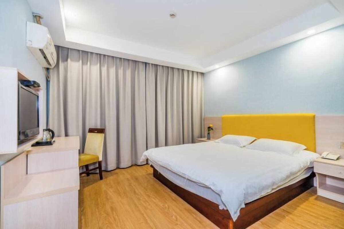 A hotel room with a bed, a chair, a desk, and a television.