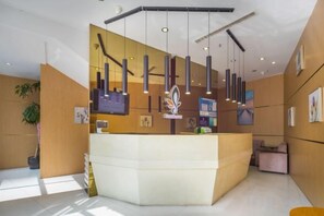 Un espace d’accueil doté d’un comptoir incurvé, d’un éclairage suspendu et d’un écran fixé au mur.