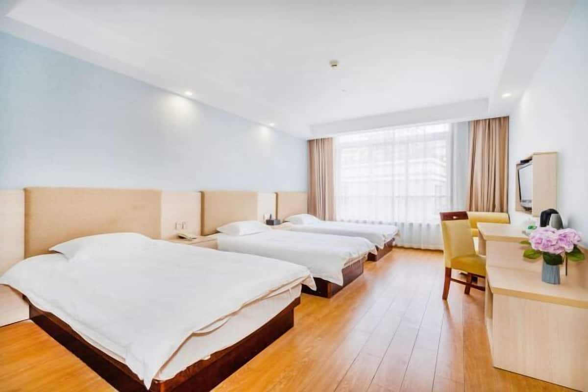A hotel room with three beds, a desk, and a chair.