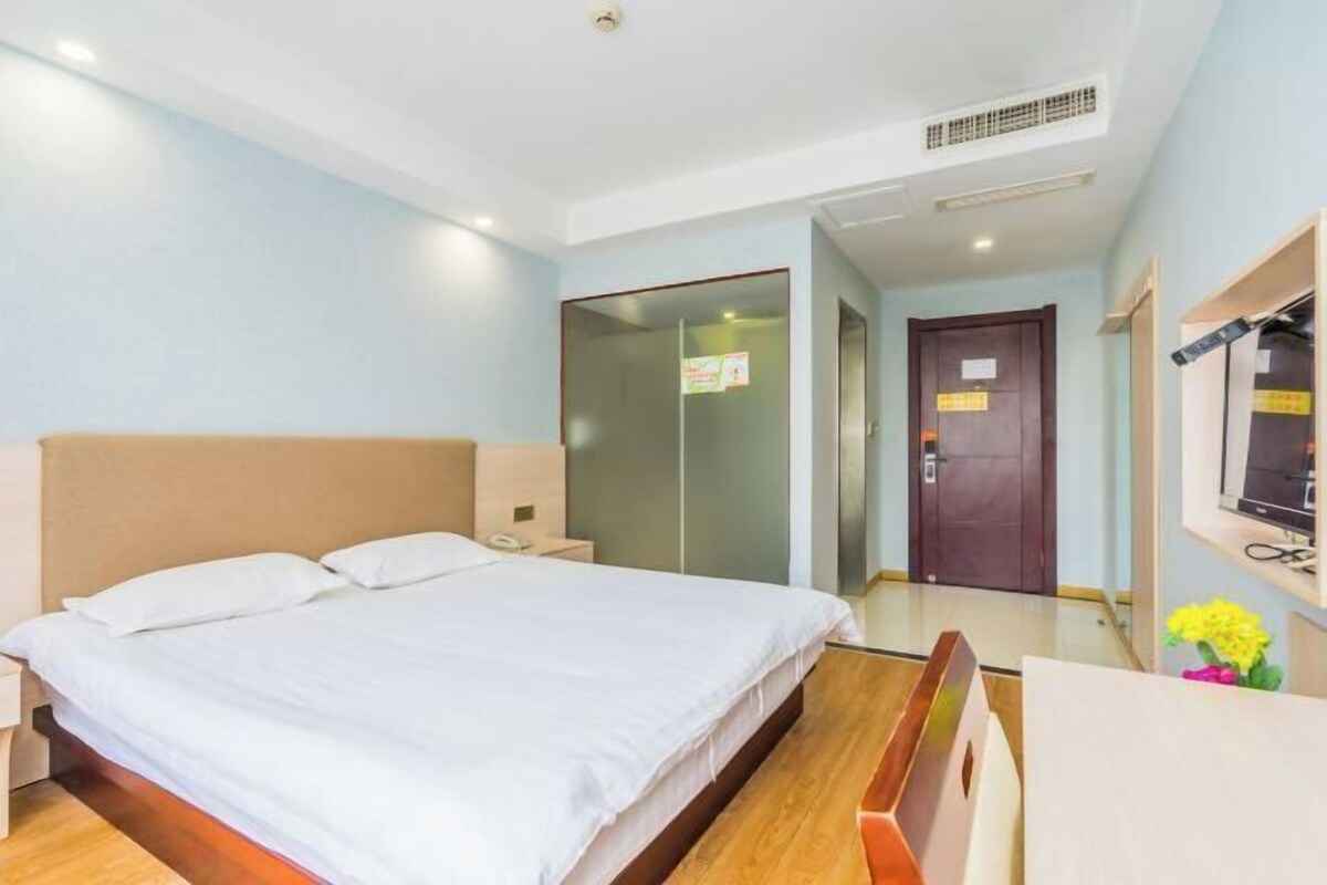 A hotel room with a bed, a desk, a mirror, and a door.