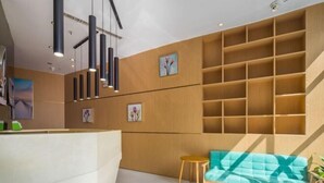 Et moderne receptionsområde med en træreception, en tealfarvet sofa og en væg med indbyggede hylder.