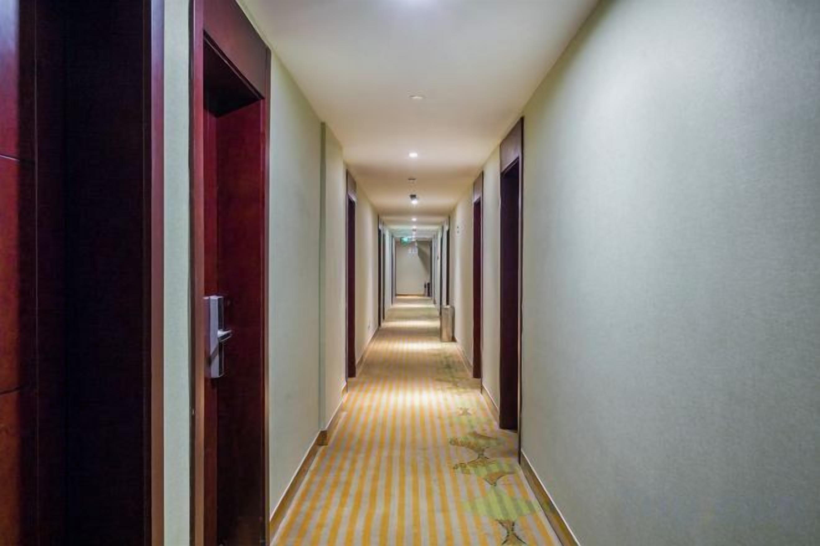 A long, narrow hotel corridor with doors on both sides and a striped carpet.