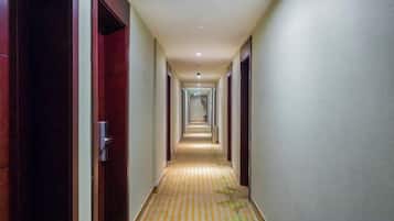 A long, narrow hotel corridor with doors on both sides and a striped carpet.