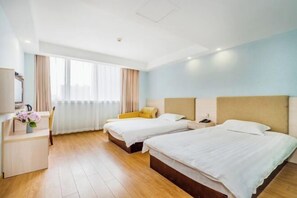 Ein Hotelzimmer mit zwei Betten, einem Schreibtisch und einem Fenster mit Vorhängen.