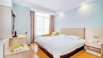 A hotel room with a bed, bedside table, lamp, and a window with curtains.