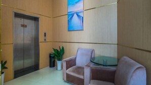 En lobby med en moderne elevator, et glasbord, en sofa og en potteplante.
