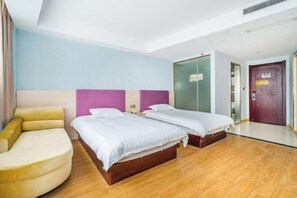 Ein Hotelzimmer mit zwei Betten, einem Schlafsofa, einem Kleiderschrank und einer Tür.