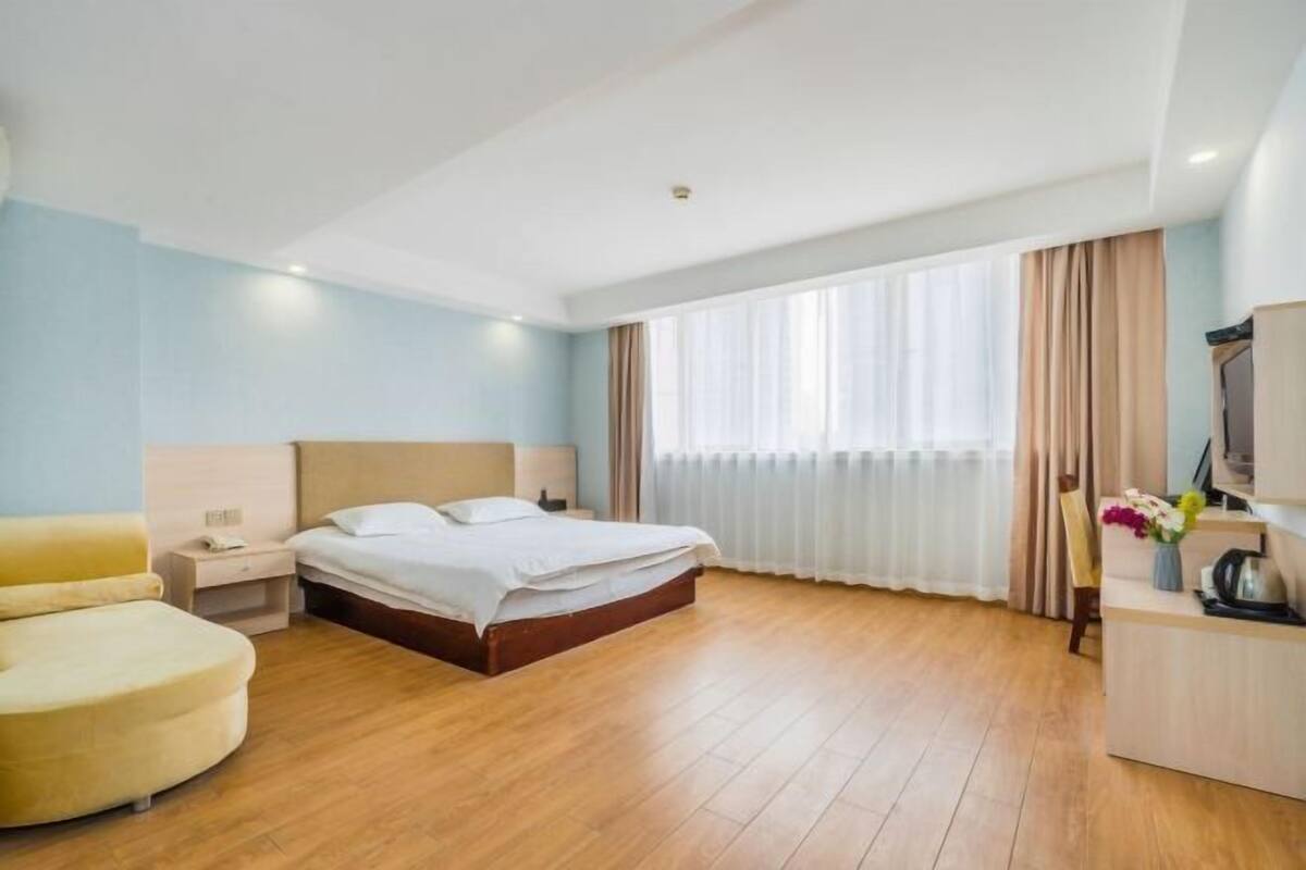 A hotel room with a bed, a desk, a chair, and a window with curtains.