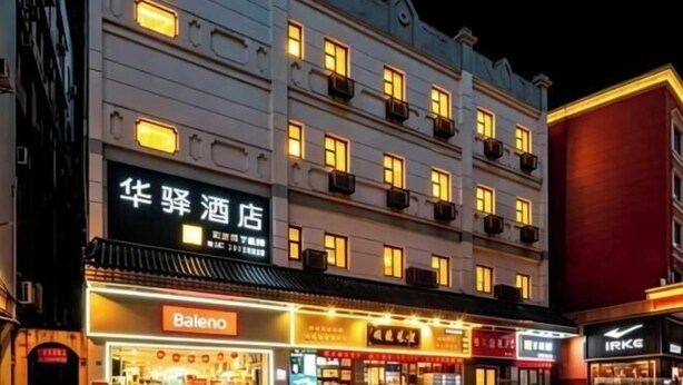 A multi-story hotel with illuminated windows and signage for 'Baleno' and 'IRKG' businesses. - Home Inn Huayi Hotel (Foshan Daliang Huagai Road Pedestrian Street Qinghuiyuan Branch) (Foshan)