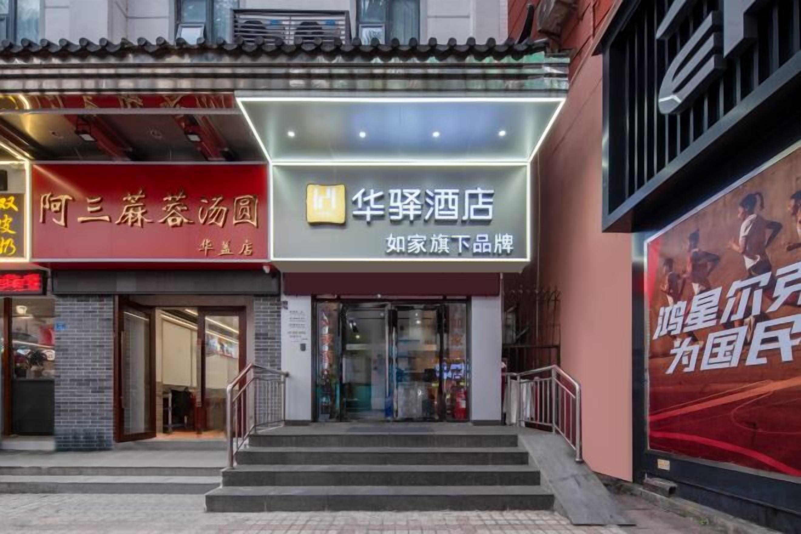 Entrada de un hotel con un cartel que dice '华辉酒店' y otro cartel que dice '阿三棉蓖汤园'.