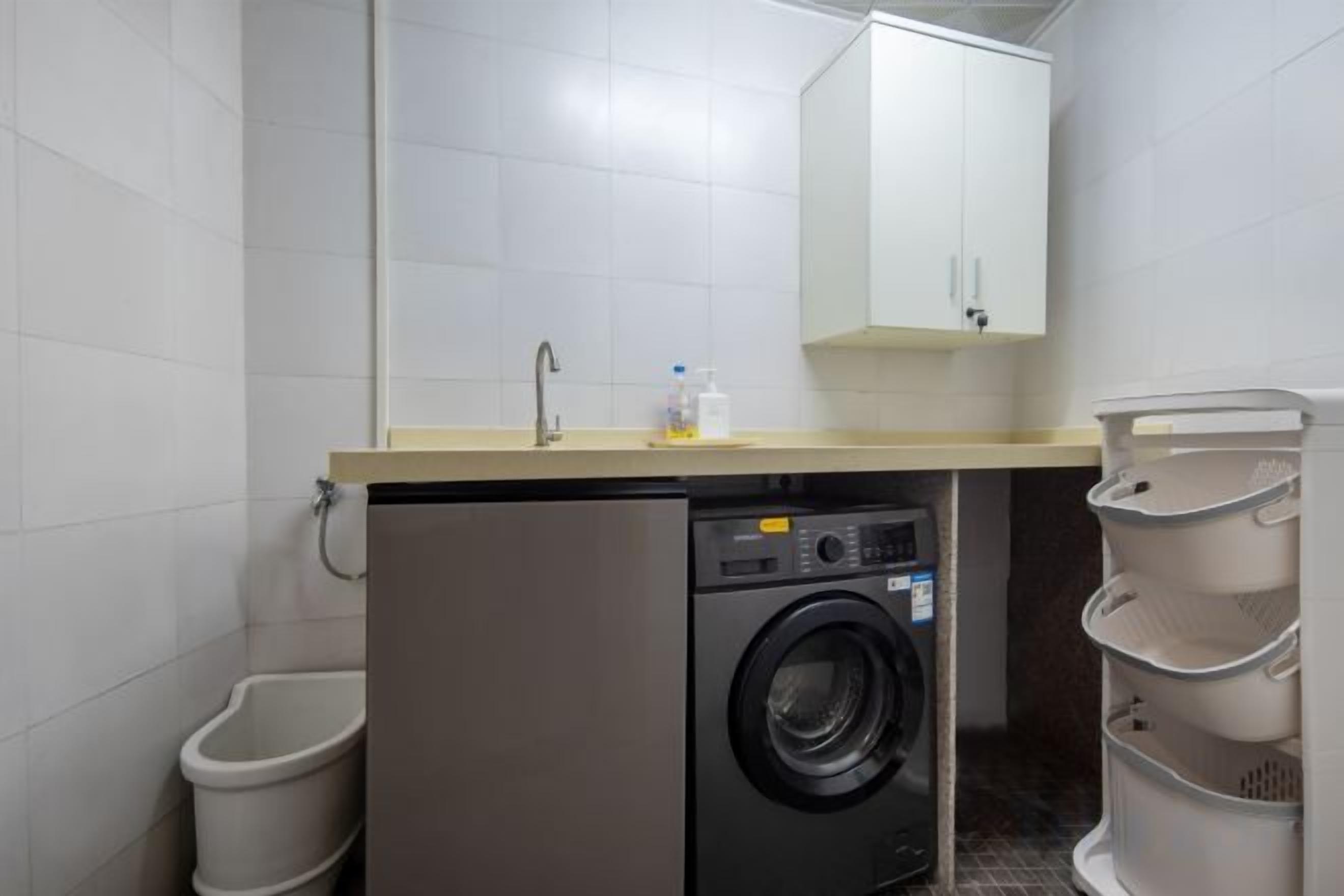 A compact laundry area with a washing machine, a sink, and a cabinet.