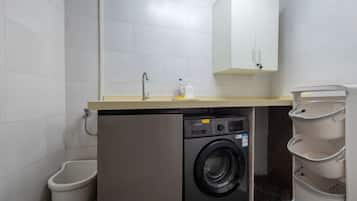 A compact laundry area with a washing machine, a sink, and a cabinet.