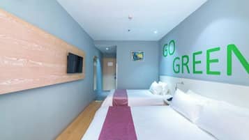 A hotel room with a bed, a TV mounted on the wall, and a 'GO GREEN' sign.