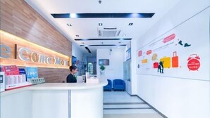 A hotel reception area with a wooden reception desk, a digital screen, and a wall with travel-related graphics. - Home Inn Huayi Hotel (Foshan Daliang Huagai Road Pedestrian Street Qinghuiyuan Branch) (Foshan)