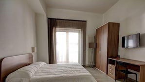 A bedroom with a bed, a desk, a chair, a wardrobe, and a TV. - Appartamento Ariel   La Perla del Mare di Polignano (Polignano a Mare)