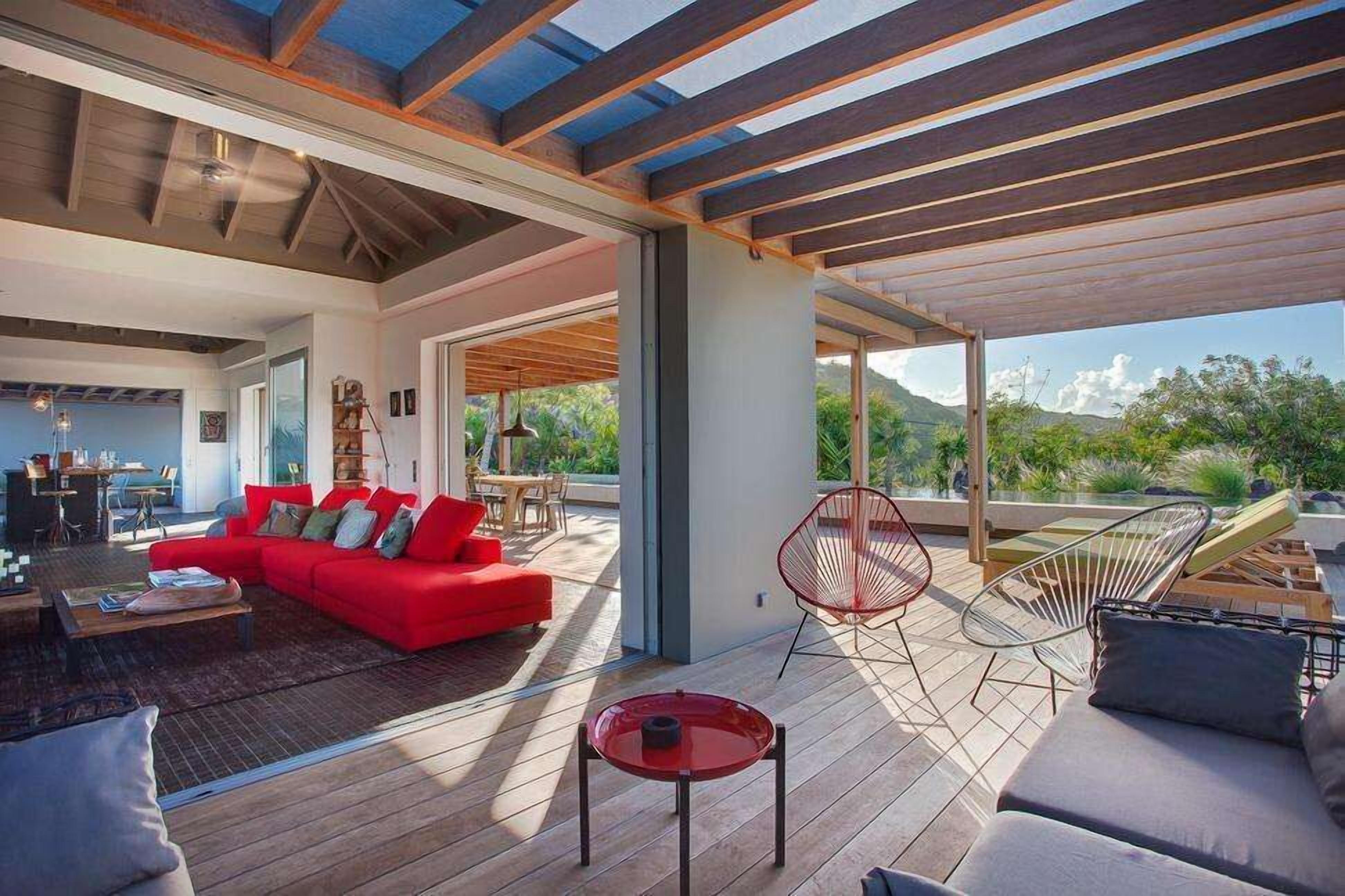 Un amplio salón con un sofá rojo, una mesa de vidrio y una silla roja.