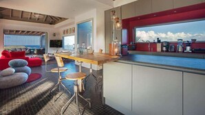 Cocina moderna con una isla grande, detalles en rojo y vistas al mar.