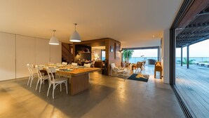 Um interior moderno com área de jantar, cozinha e vista para o mar.
