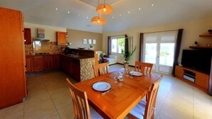 Una cocina amplia con armarios de madera, una mesa de comedor para cuatro personas y un ventanal que proporciona luz natural.