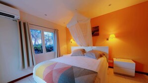 Un dormitorio con cama, mesita de noche, ventana con cortinas y una lámpara de pared.
