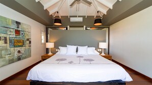 A modern hotel room with a large bed, two bedside tables with lamps, a ceiling fan, and a large abstract painting on the wall. - Vague Bleue (1/3 Rooms) (Lurin)