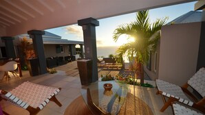 A modern outdoor patio with lounge chairs, a glass-top table, and a view of the ocean. - Vague Bleue Luxury villa (Lurin)
