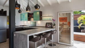 A modern kitchen with a central island, bar stools, pendant lights, and teal cabinets. - Vague Bleue Luxury villa (Lurin)