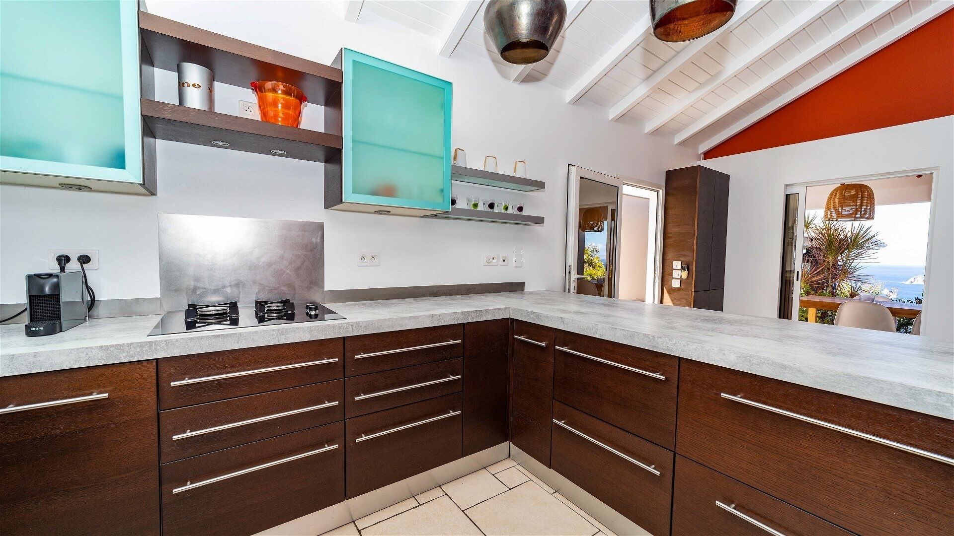 A modern kitchen with dark wooden cabinets, a stainless steel stove, and a teal backsplash.
