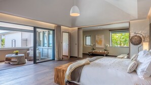 A spacious bedroom with a large bed, a wooden bench, and a view of the outdoors. - Beautiful Villa K Luxury villa (Anse Des Cayes)