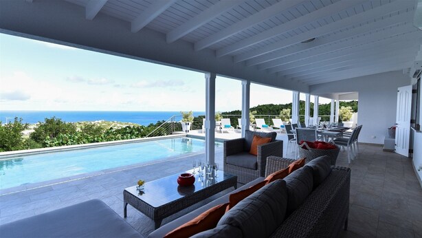 A modern outdoor lounge area with a pool, seating, and a view of the ocean. - Au Coeur du Rocher (1/3 Rooms) (Marigot)