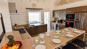 A modern kitchen with a dining area, stainless steel appliances, and a view of the outdoors. - Au Coeur du Rocher (1/3 Rooms) (Marigot)