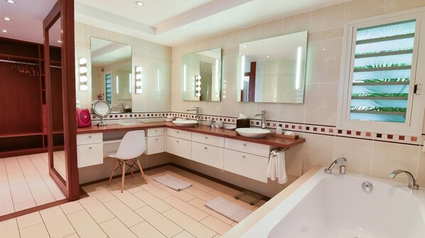Une salle de bain moderne avec un grand miroir, deux lavabos, un meuble-lavabo et une baignoire.