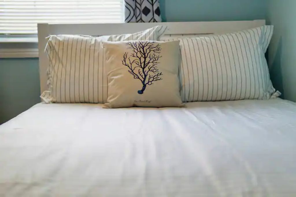 Een bed met witte lakens en gestreepte kussens.