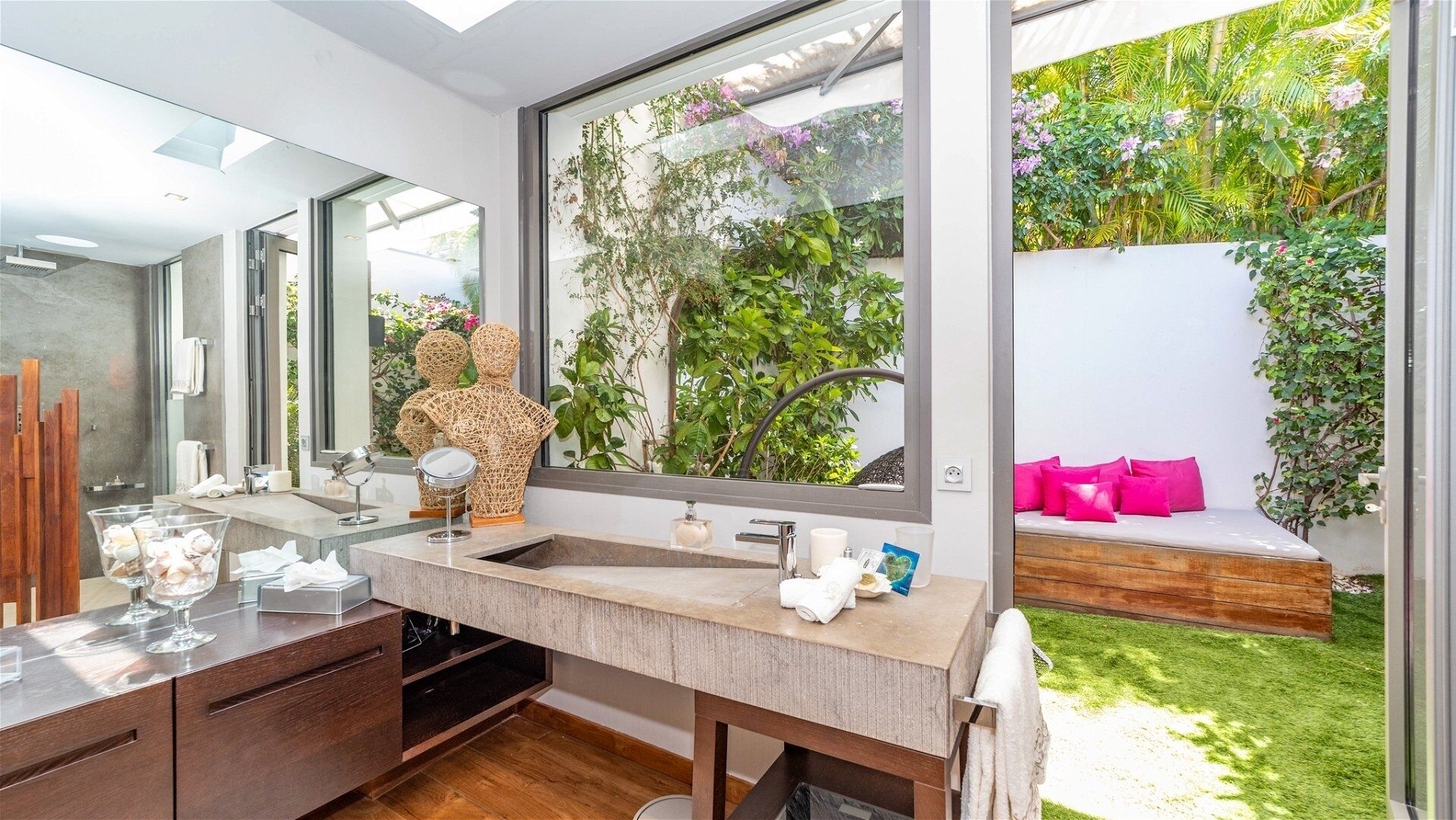 Un bagno moderno con un'ampia finestra, un mobile bagno in legno e vista su un giardino.
