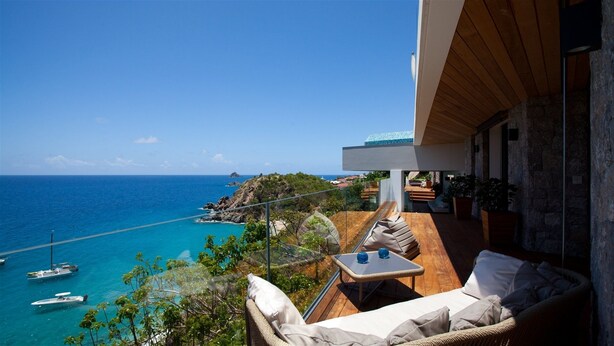 Un balcon avec vue sur la mer, une terrasse en bois et du mobilier d’extérieur.