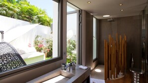 Une salle de bain moderne dotée d’une grande fenêtre, d’un lavabo avec un miroir et d’un espace douche agrémenté d’éléments en bois.