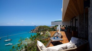 A balcony with a view of the sea, a wooden deck, and outdoor furniture. - Beautiful Vitti Luxury villa (Gustavia)