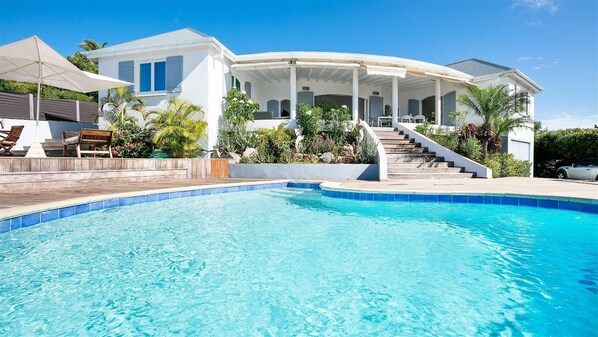 Une maison moderne dotée d’une piscine, d’un patio couvert et d’un escalier menant à l’intérieur.