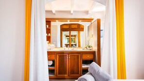 Une salle de bain avec un meuble-lavabo en bois, un grand miroir et une serviette sur le sol.
