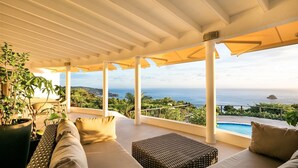 A covered outdoor seating area with a pool, overlooking a coastal landscape. - Taniko (2/3 Rooms) Luxury villa (Colombier)